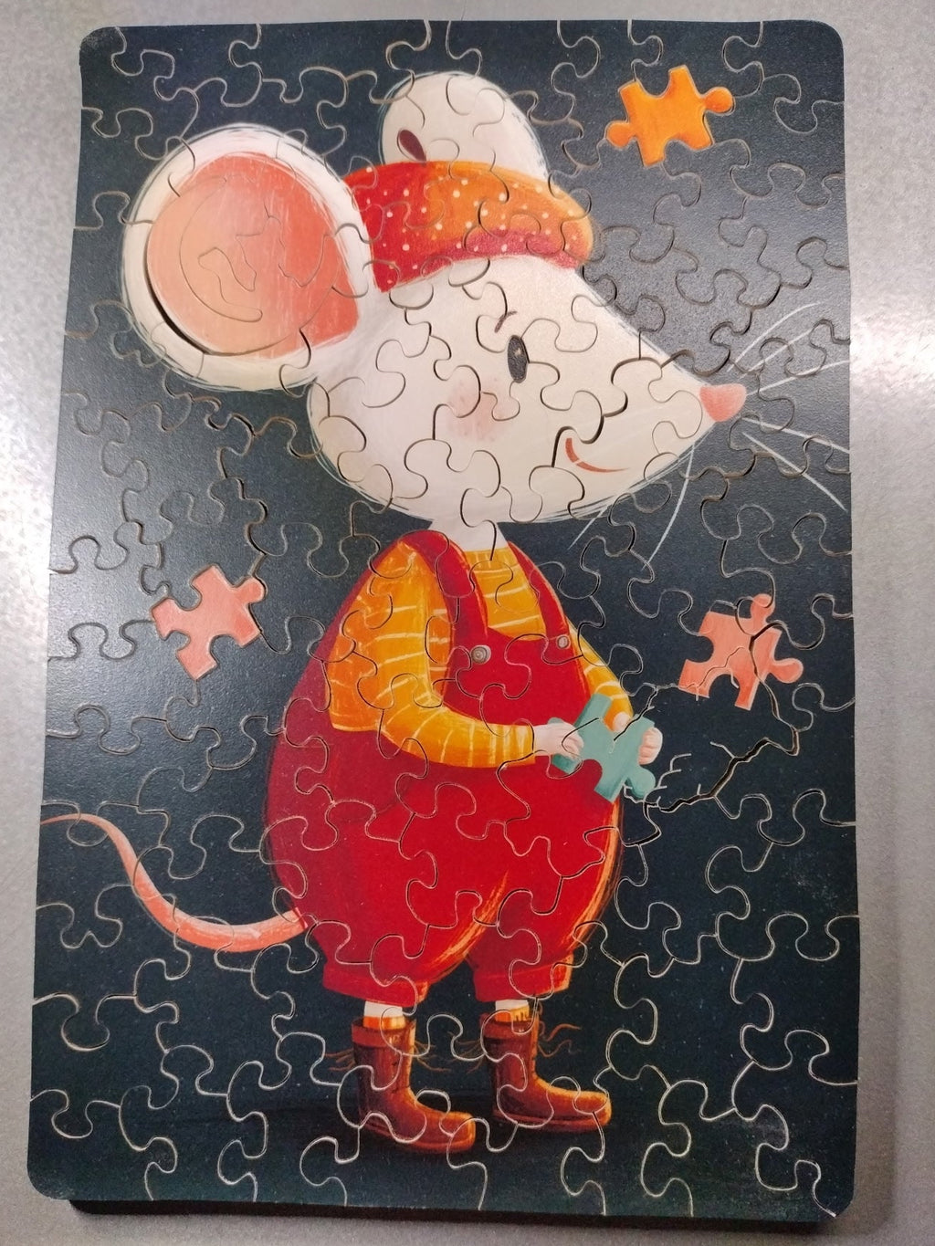 Jigsaw puzzle of a mouse in a red outfit on a dark background