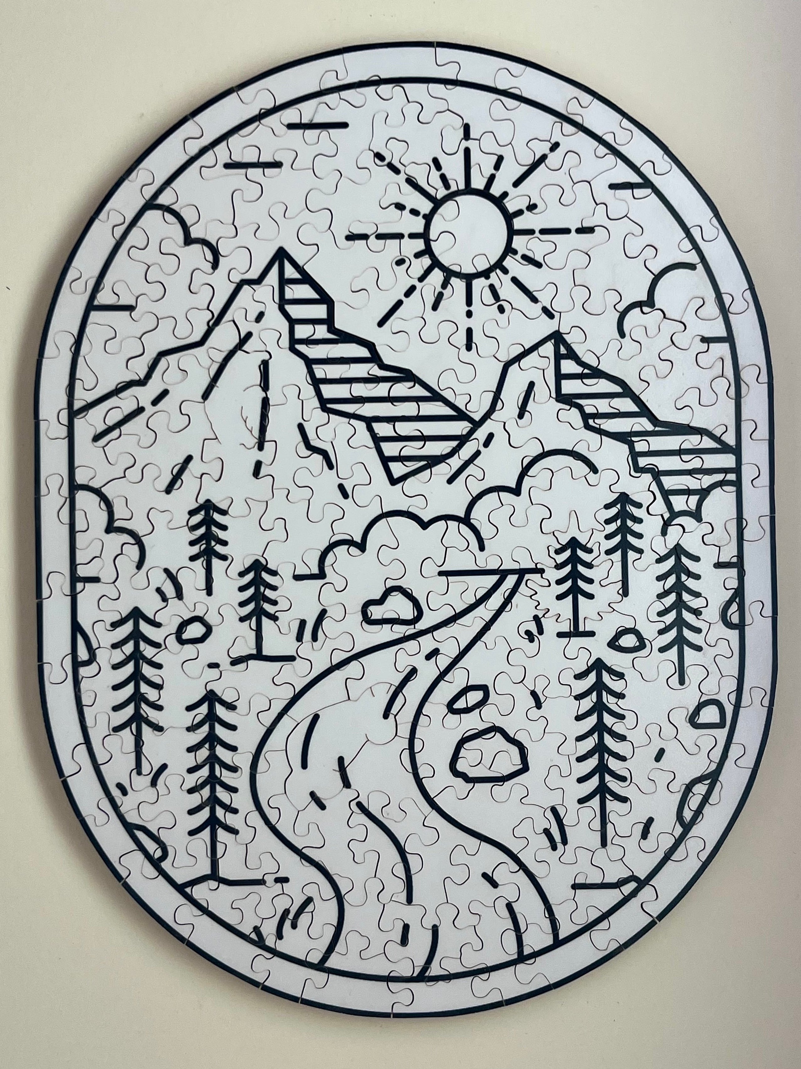 A completed jigsaw puzzle depicting a stylized mountain landscape with sun, trees, and a winding road, arranged in a circular frame.