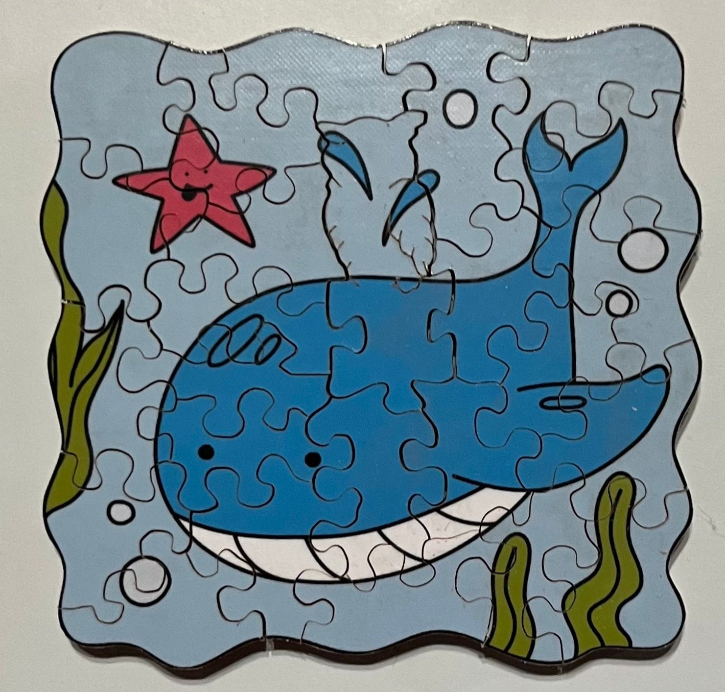 A mini jigsaw puzzle depicting a blue whale in an underwater setting with sea stars and bubbles.