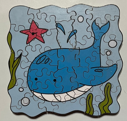 A mini jigsaw puzzle depicting a blue whale in an underwater setting with sea stars and bubbles.